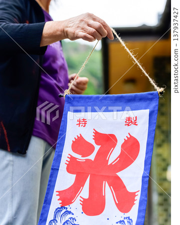 一位女士正在戶外準備一面刨冰專用旗幟。 137937427