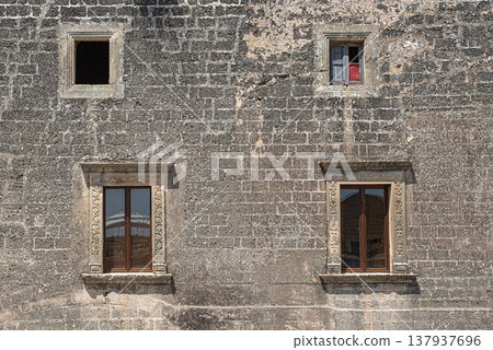 Ancient stone wall with different window styles 137937696