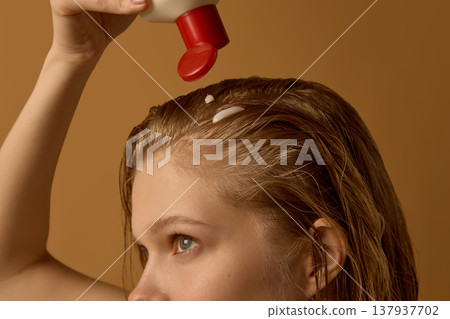 Applying hair product from bottle onto scalp close up. 137937702
