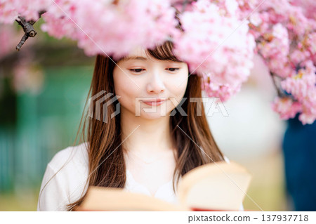 一位年輕女子在櫻花樹前讀書 137937718