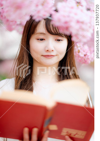 A young woman reading in front of a cherry tree 137937720