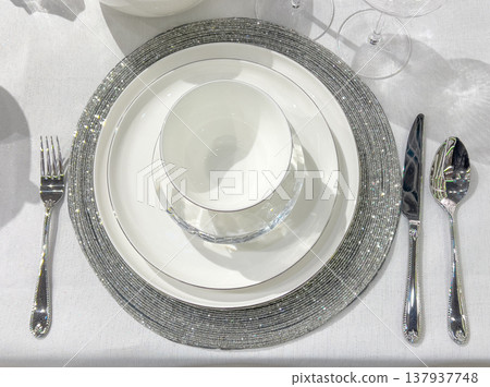 Elegant dining table setting with white dinnerware and silver cutlery 137937748