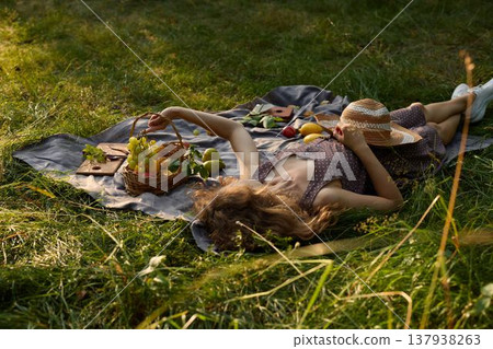 Woman resting in open field with basket of apples nearby 137938263