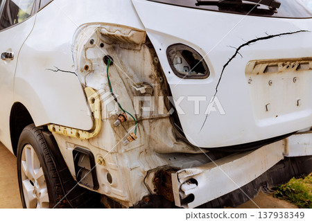Damaged car is parked on street cracked rear end with exposed wires parts 137938349