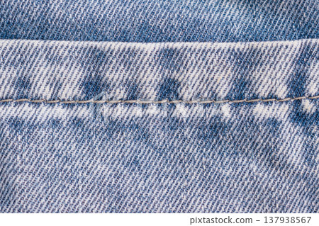 Close-up of a classic blue denim seam with contrasting orange double stitching. Detailed indigo twill weave and natural wear create a stylish, structural background Close-up of a classic blue denim seam with contrasting orange double stitching. Detailed indigo twill weave and natural wear create a stylish, structural background 137938567