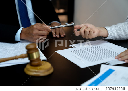 lawyer handing a pen to a client or business associate to sign a contract 137939336