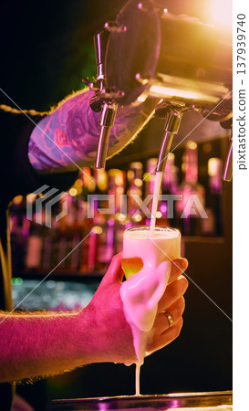 Close up bartender hand pouring draft beer with thick foam spilling over glass. Close up bartender hand pouring draft beer with thick foam spilling over glass. 137939740