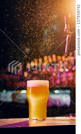 Fresh beer glass on bar counter with sparkling drops and colorful nightlife lights. 137939742