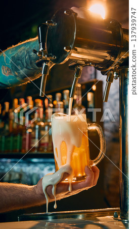 Draft beer pouring into glass mug with excessive foam spilling over bartender hand 137939747