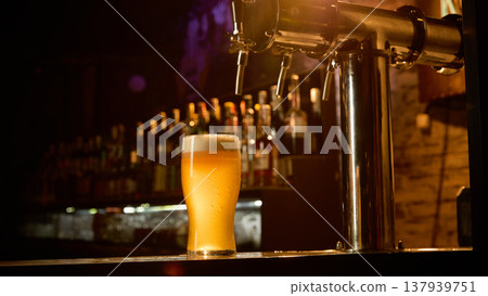 Fresh draft beer glass on bar counter with soft foam in cozy pub interior. 137939751