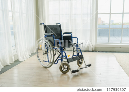 Empty wheelchair waiting for patient services in living room retirement home hospital. Chair for people with disability at home. Handicap accessible symbol. Health care medical lonely elderly sick Empty wheelchair waiting for patient services in living room retirement home hospital. Chair for people with disability at home. Handicap accessible symbol. Health care medical lonely elderly sick 137939807