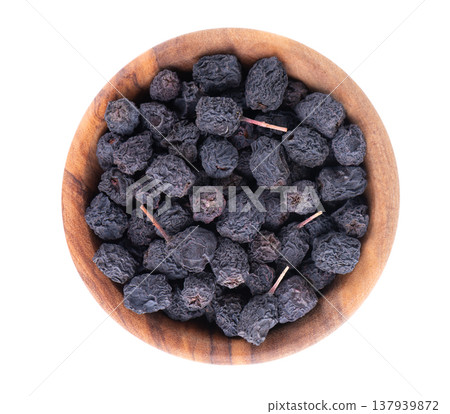 Dried aronia berries isolated on white background. Dry black chokeberry in wooden bowl. Clipping path. Top view. Dried aronia berries isolated on white background. Dry black chokeberry in wooden bowl. Clipping path. Top view. 137939872