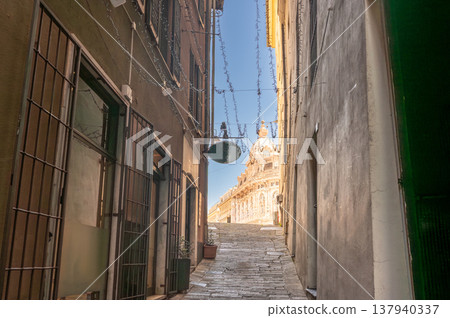 Genoa, liguria, italy. May 18,2024. Narrow cobbled street in trieste old town leading to a historic church dome under a bright summer sky, empty medieval alleyway Genoa, liguria, italy. May 18,2024. Narrow cobbled street in trieste old town leading to a historic church dome under a bright summer sky, empty medieval alleyway 137940337