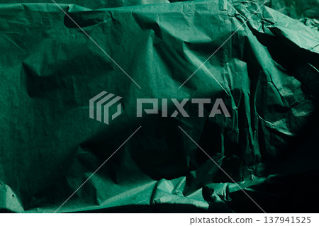 Dark green crumpled tissue paper texture with moody shadows. Abstract background, wrinkled emerald paper, organic folds, minimalist photography. Dark green crumpled tissue paper texture with moody shadows. Abstract background, wrinkled emerald paper, organic folds, minimalist photography. 137941525