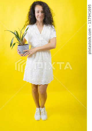 Woman holding potted plant showing plant care and green living Woman holding potted plant showing plant care and green living 137941695
