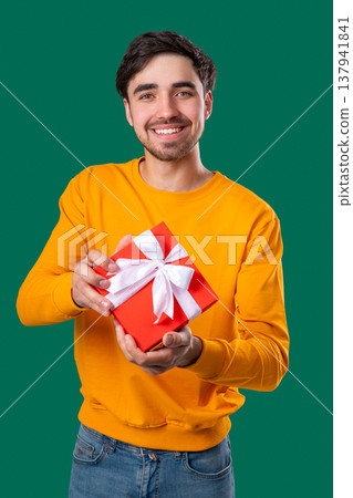 Happy Young Casual Man Gift Box Green Background. Guy Smiling, Whats Inside. Happy Young Casual Man Gift Box Green Background. Guy Smiling, Whats Inside. 137941841