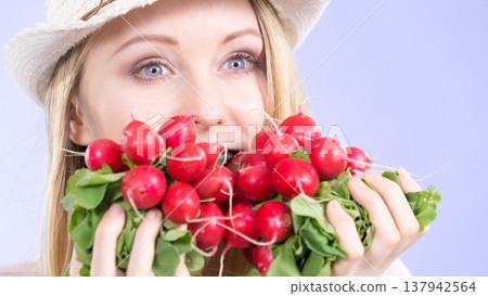 woman holding radish close to face woman holding radish close to face 137942564