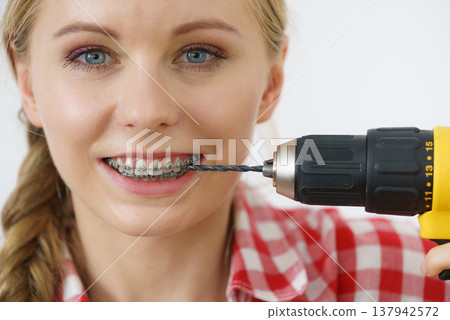 Woman with braces using drill on her teeth Woman with braces using drill on her teeth 137942572