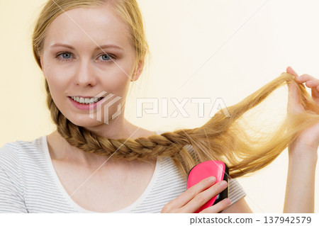 Blonde girl with long braid hair holds brush Blonde girl with long braid hair holds brush 137942579