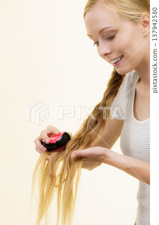 Blonde girl with long braid hair holds brush 137942580