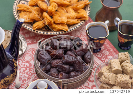Dried dates and halva. Sweet fruit food. Dessert with coffee cup. Date bowl on table Dried dates and halva. Sweet fruit food. Dessert with coffee cup. Date bowl on table 137942719