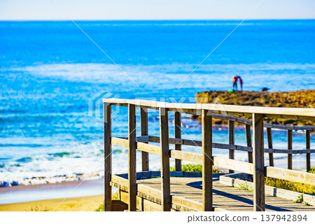 Beach with wooden path to sea water. Beach with wooden path to sea water. 137942894