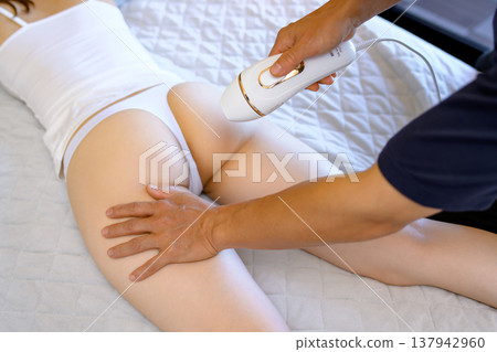 女性在伴侶（男友、丈夫）的幫助下，俯臥使用家用除毛儀進行 VIO 除毛。 137942960