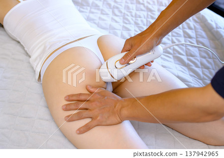 女性在伴侶（男友、丈夫）的幫助下進行 VIO 脫毛，她們面朝下躺著；使用家用除毛設備；修剪。 137942965