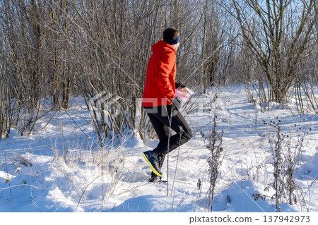 Orienteer in bright red jacket runs through frosty snowy forest Orienteer in bright red jacket runs through frosty snowy forest 137942973