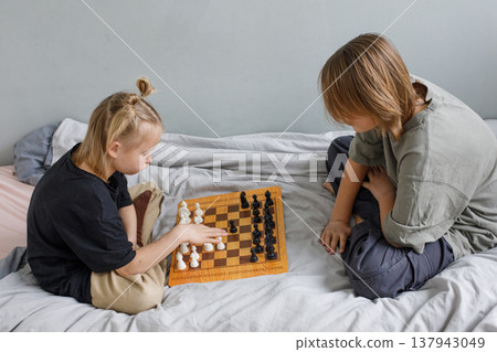 Leisure activity. Two cute children playing chess at home Leisure activity. Two cute children playing chess at home 137943049