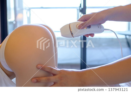 Women getting help from their partners (boyfriends, husbands) for VIO hair removal; on all fours; using a home hair removal device; trimming up. 137943121