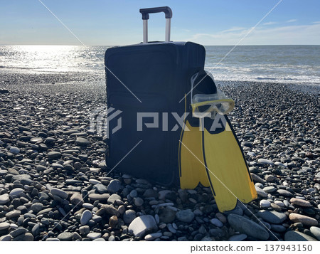 Snorkeling gear and suitcase on a rocky beach during the day wit Snorkeling gear and suitcase on a rocky beach during the day wit 137943150