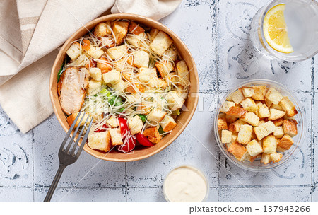 Caesar salad in a paper container, take it on the way, with sauce and croutons, on the table, snack, no people, 137943266