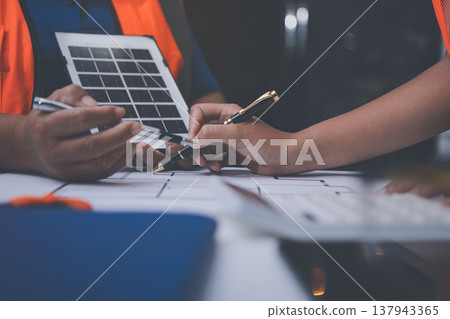 engineer and an architect reviewing blueprints and construction plans together at a bustling construction site engineer and an architect reviewing blueprints and construction plans together at a bustling construction site 137943365