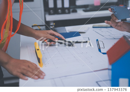 engineer and an architect reviewing blueprints and construction plans together at a bustling construction site engineer and an architect reviewing blueprints and construction plans together at a bustling construction site 137943376