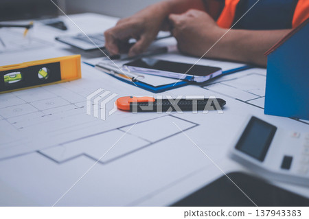 engineer and an architect reviewing blueprints and construction plans together at a bustling construction site engineer and an architect reviewing blueprints and construction plans together at a bustling construction site 137943383