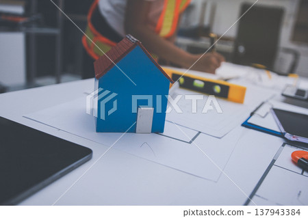engineer and an architect reviewing blueprints and construction plans together at a bustling construction site 137943384