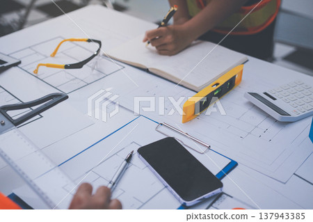 engineer and an architect reviewing blueprints and construction plans together at a bustling construction site engineer and an architect reviewing blueprints and construction plans together at a bustling construction site 137943385