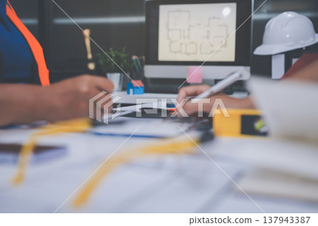 engineer and an architect reviewing blueprints and construction plans together at a bustling construction site engineer and an architect reviewing blueprints and construction plans together at a bustling construction site 137943387