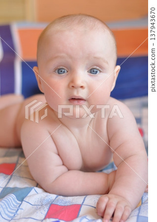 Curious Baby Lying on Colorful Bedspread Curious Baby Lying on Colorful Bedspread 137943670