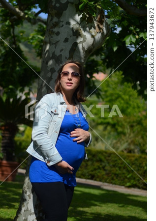 Pregnant Woman Relaxing Outdoors in Sunglasses Pregnant Woman Relaxing Outdoors in Sunglasses 137943672