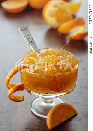 Orange jam in a glass dessert bowl on an old wooden table. 137943843