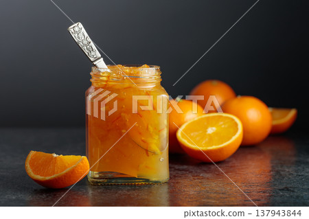 Homemade orange jam in a glass jar on a black table. 137943844