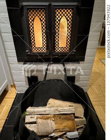 Firewood in a bag in front of a burning fireplace in a cozy house Firewood in a bag in front of a burning fireplace in a cozy house 137943922