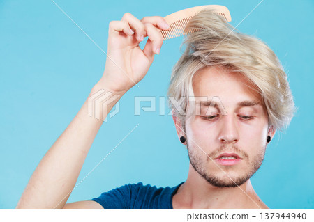 Man with stylish haircut combing his hair Man with stylish haircut combing his hair 137944940