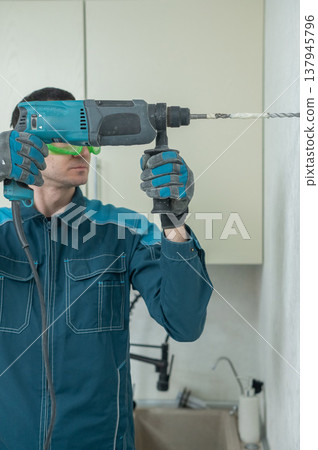 A man drills into a wall. A man drills into a wall. 137945796