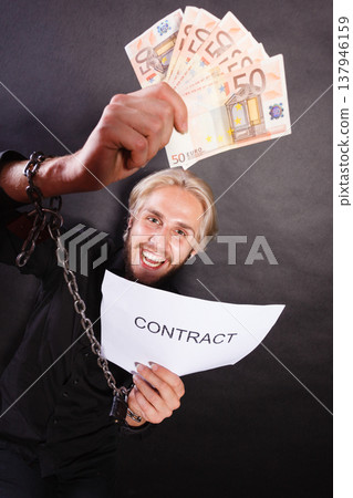 Man with chained hands holding contract and money 137946159