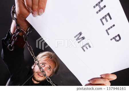 Man with chained hands holding help me sign 137946161