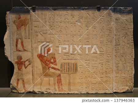 一塊古埃及彩繪浮雕石碑，描繪了一個坐像和象形文字。 137946363