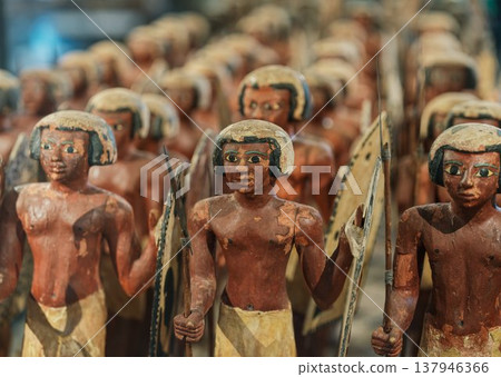 A group of wooden soldier statues from ancient Egypt, each holding a spear and shield. 137946366